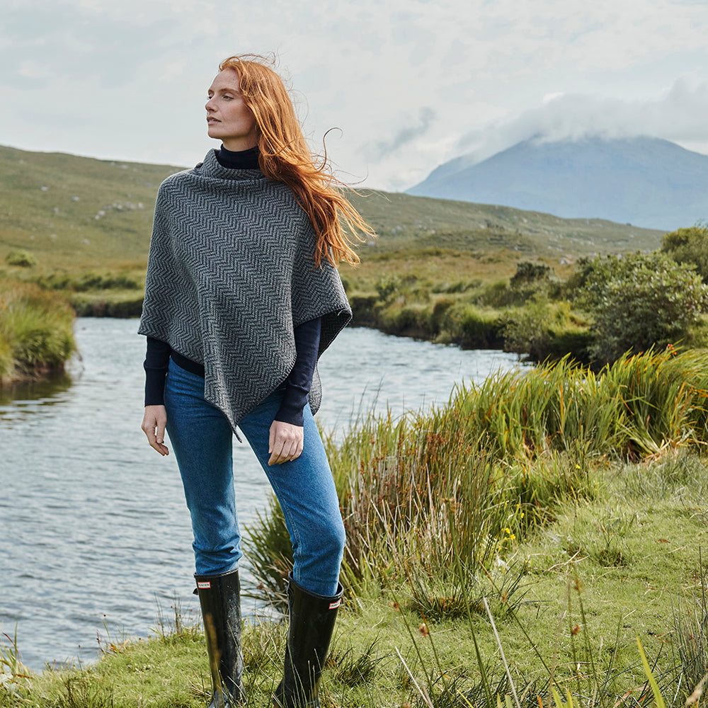 Charcoal herringbone poncho with buttons, woman by river