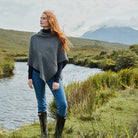 Charcoal herringbone poncho with buttons, woman by river